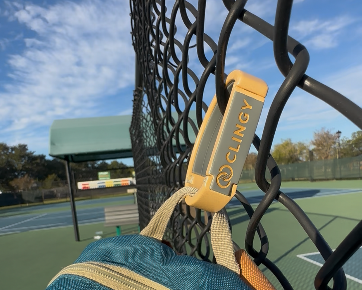 Clingy hook holding a bag on a fence, keeping it off dirty ground outdoors
