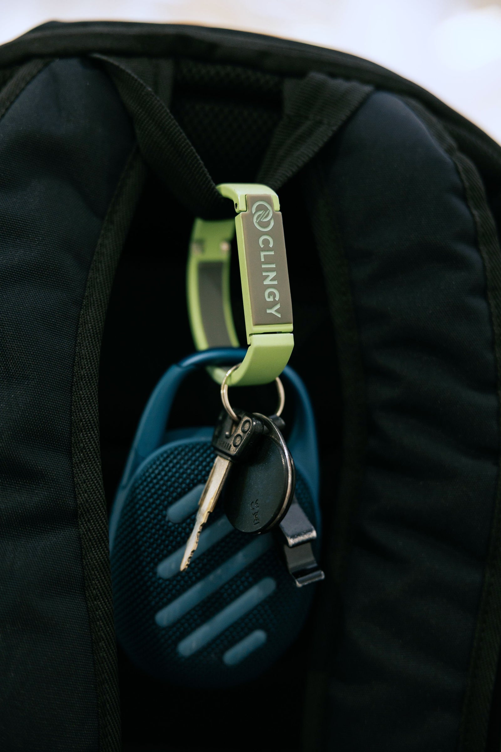 ClingyHook clipped to a backpack strap holding a set of keys and speaker.